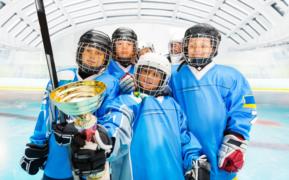 Kids holding a hockey trophy.